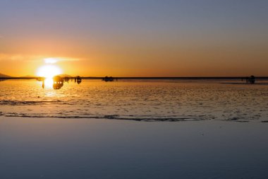 Gün batımında Bolivya Salar de Uyuni, tuz düzlüklerinde gökyüzünün muhteşem bir yansıması, unutulmaz ve gerçeküstü bir manzara yaratıyor.