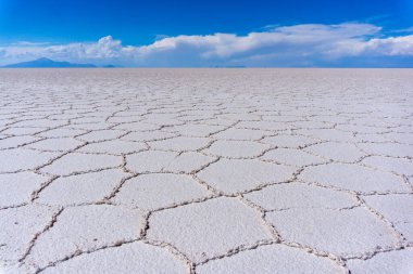 Geometrik Tuz oluşumlarıyla Salar de Uyuni 'nin nefes kesici manzarası ve Bolivya Altiplanosundaki Güneş ışığını yansıtan çatlak beyaz yüzey