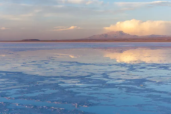 Uyuni Tuz Düzlüğü üzerinde gün batımında renkli gökyüzü Bulutlar ve su Bolivya 'daki canlı renkleri yansıtıyor