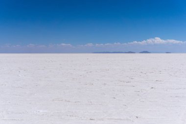 Bolivya 'da Salar de Uyuni sonsuz beyaz tuz çölü ve açık mavi gökyüzünü insansız ve dokusuz gösteriyor.