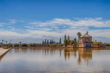 Menara bahçeleri, arka planda Atlas Dağları, Marakeş, Fas karlı havuz ve pavyonu yansıtıyor..
