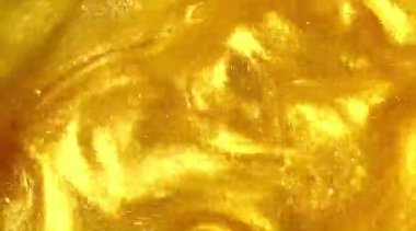 Liquid gold motion organic background. Shine glitter fluid metallic yellow color paint. Texture abstract mica powder cloud swirling underwater.