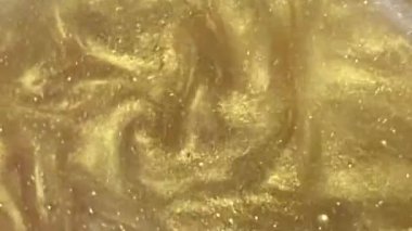 Liquid gold motion organic background. Shine glitter fluid metallic yellow color paint. Texture abstract mica powder cloud swirling underwater.