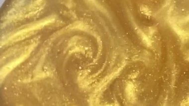 Liquid gold motion organic background. Shine glitter fluid metallic yellow color paint. Texture abstract mica powder cloud swirling underwater.