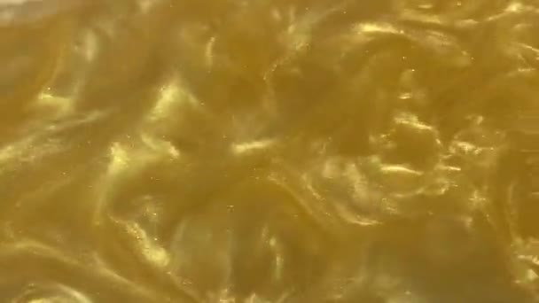 液体金の動き有機的背景 輝き輝く流体金属イエローカラーペイント テクスチャ抽象的なミカパウダークラウド水中を渦巻く — ストック動画