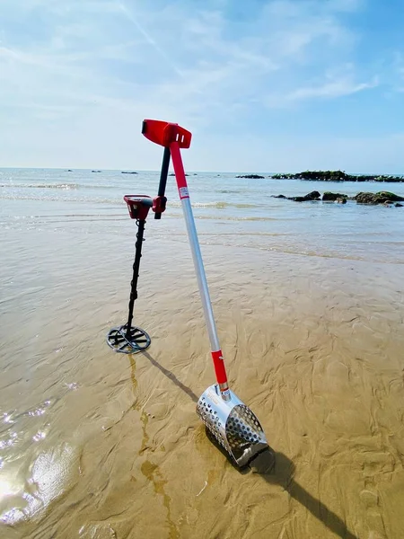 stock image metal detecting equipment detector and sand scoop on the beach with ocean sand waves and sky behind background with copy space