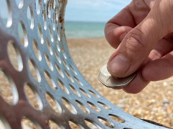 海滩沙坑中的硬币 带有金属探测器线圈 背景在沙滩上 有复制空间 — 图库照片
