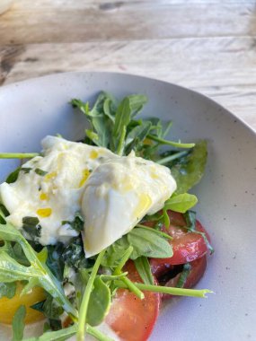 Diyet ve sağlıklı salata roka, miras domatesler, mozzarella peyniri ve ahşap kaplama zeytinyağı.