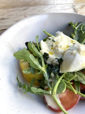 Diyet ve sağlıklı salata roka, miras domatesler, mozzarella peyniri ve ahşap kaplama zeytinyağı.