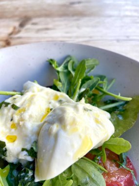 Diyet ve sağlıklı salata roka, miras domatesler, mozzarella peyniri ve ahşap kaplama zeytinyağı.