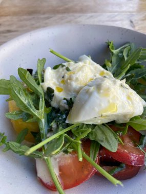 Diyet ve sağlıklı salata roka, miras domatesler, mozzarella peyniri ve ahşap kaplama zeytinyağı.