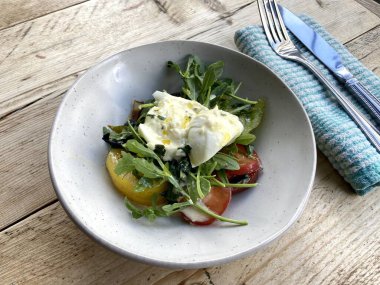 Diyet ve sağlıklı salata roka, miras domatesler, mozzarella peyniri ve ahşap kaplama zeytinyağı.