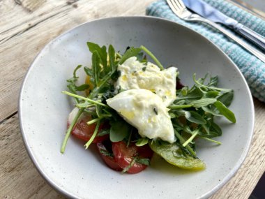 Diyet ve sağlıklı salata roka, miras domatesler, mozzarella peyniri ve ahşap kaplama zeytinyağı.