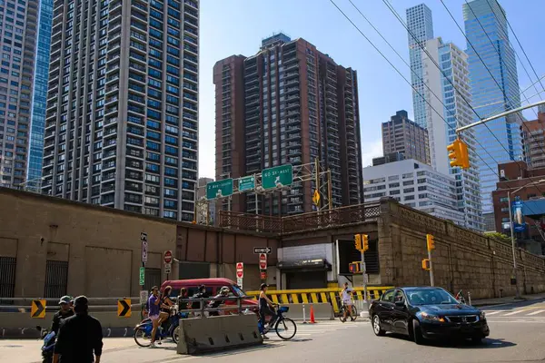 New York, New York, ABD - 31 Ekim 2022: Bisikletçiler ve arabalar arka planda gökdelenlerle birlikte Manhattan 'daki E 60. Cadde' deki Queensboro Köprüsü 'nden çıkıyorlar