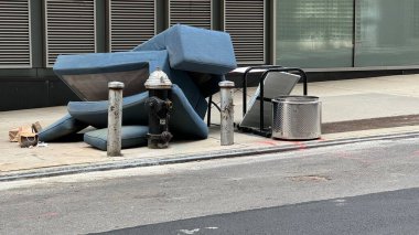 New York, New York - 30 Mart 2024: Bir kanepe ve yastıklar şehir merkezindeki kaldırımda bir yığın halinde atılıyor.