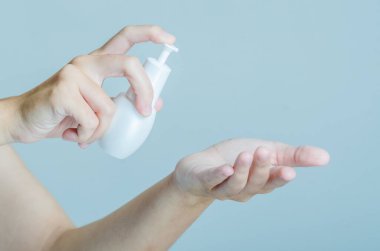 Cilt bakımı için pompa şişesi kullanan yakın çekim eller. Görüntü, günlük kişisel bakım rutinlerinin basitliği ve kolaylığına odaklanır..