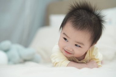 Karnında yumuşak, desenli bir yastığa uzanmış bir bebeğin yakın plan çekimi. Bebeğin şaşı ve meraklı ifadesi, çevreleriyle ilgilenirken çok değerli bir erken gelişim anını yakalar..