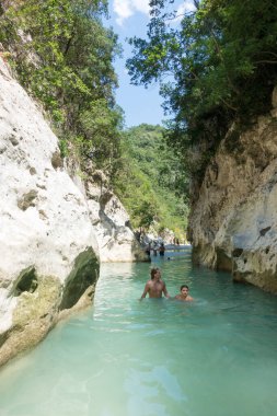 19 Ağustos 2023 - Parga, Yunanistan - Kaplıcalara yakın Acheron nehrinin kanyonunda insanların ılık bir yaz gününde soğuk suyun tadını çıkardıkları inanılmaz doğal manzara. 
