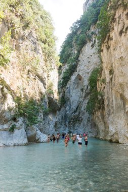 19 Ağustos 2023 - Parga, Yunanistan - Kaplıcalara yakın Acheron nehrinin kanyonunda insanların ılık bir yaz gününde soğuk suyun tadını çıkardıkları inanılmaz doğal manzara. 