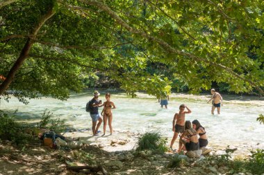 19 Ağustos 2023 - Parga, Yunanistan - Kaplıcalara yakın Acheron nehrinin kanyonunda insanların ılık bir yaz gününde soğuk suyun tadını çıkardıkları inanılmaz doğal manzara. 