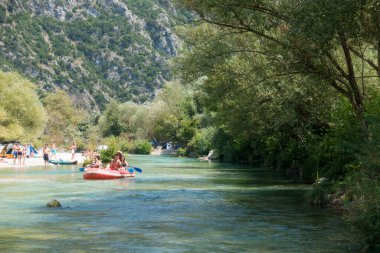 19 Ağustos 2023 - Parga, Yunanistan - Kaplıcalara yakın Acheron nehrinin kanyonunda insanların ılık bir yaz gününde soğuk suyun tadını çıkardıkları inanılmaz doğal manzara. 