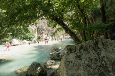19 Ağustos 2023 - Parga, Yunanistan - Kaplıcalara yakın Acheron nehrinin kanyonunda insanların ılık bir yaz gününde soğuk suyun tadını çıkardıkları inanılmaz doğal manzara. 