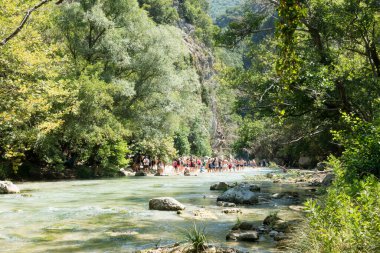 19 Ağustos 2023 - Parga, Yunanistan - Kaplıcalara yakın Acheron nehrinin kanyonunda insanların ılık bir yaz gününde soğuk suyun tadını çıkardıkları inanılmaz doğal manzara. 