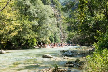 19 Ağustos 2023 - Parga, Yunanistan - Kaplıcalara yakın Acheron nehrinin kanyonunda insanların ılık bir yaz gününde soğuk suyun tadını çıkardıkları inanılmaz doğal manzara. 