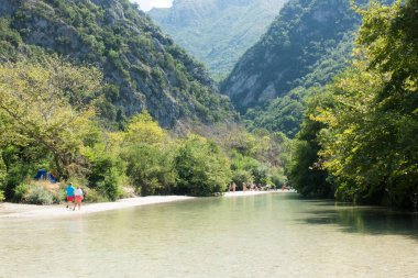 19 Ağustos 2023 - Parga, Yunanistan - Kaplıcalara yakın Acheron nehrinin kanyonunda insanların ılık bir yaz gününde soğuk suyun tadını çıkardıkları inanılmaz doğal manzara. 