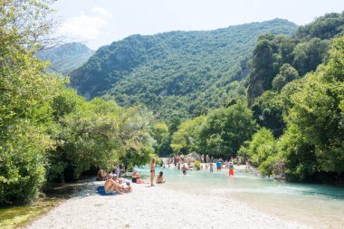 19 Ağustos 2023 - Parga, Yunanistan - Kaplıcalara yakın Acheron nehrinin kanyonunda insanların ılık bir yaz gününde soğuk suyun tadını çıkardıkları inanılmaz doğal manzara. 