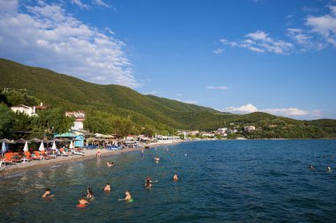 August 11th 2023 - Menidi, Greece - The beach in Menidi village, with people enjoying the sea, in the Ambracian gulf, Aetolia-Acarnania, Greece clipart