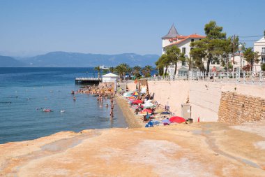 June 25th 2024 - Aidipsos, Greece - The waterfront of Aidipsos, a Greek town in North Evia famous for its hot springs and spas, with lots of people enjoying the free warm water spa clipart