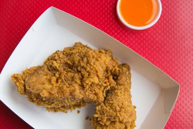 Kırmızı arka planda kızarmış tavuk ve biber sosu.