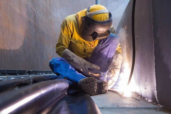 Male  worker wearing protective clothing and repair welding patition plate industrial construction oil and gas or  storage tank inside confined spaces.
