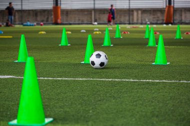 Futbol taktikleri çimenlik alanda ve arka planda çocukları eğitmek için futbol sahası konisi.