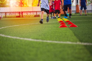 Futbol akademisinde çocukları eğitmek için engelli çimenlik alanda futbol taktikleri.