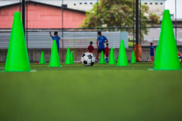 サッカーのボール戦術 サッカーのトレーニングの背景の訓練の子供のための芝場のコーン ストック画像