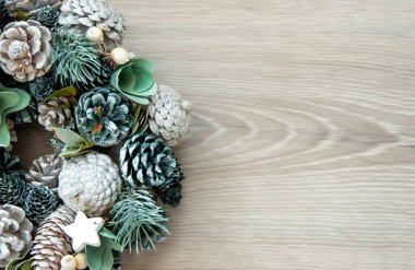 Noel arkaplanı - tahta bir arka planda koni ve dallardan oluşan bir çelenk