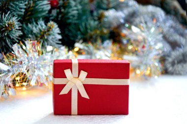 Noel kompozisyonu köknar ağacı dalları, kırmızı hediye kutusu ve altın renkli çelenk renginde gümüş süslemeler.