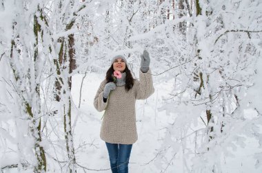 Kışın karlı bir ormanda elinde pembe bir çiçekle gülümseyen güzel bir esmer.