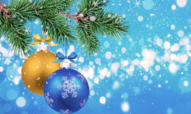 Noel arkaplanı köknar dalları ve Noel sarısı ve mavi topları ile mavi arka planda Bokeh