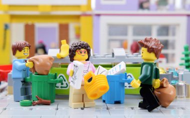 Lego minyatürleri, beyaza izole edilmiş farklı maddelerden oluşan bir çöpü kaldırıyor. Popüler plastik oyuncağın editoryal çizimi.