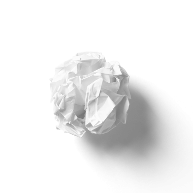 Buruşmuş beyaz bir kağıt parçası parlak bir arka plana yumuşak bir gölge düşürüyor..