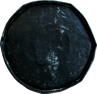 Yuvarlak, siyah, aşınmış yüzeyi olan sekizgen bir nesne, muhtemelen tepsi ya da dekoratif bir tabak..