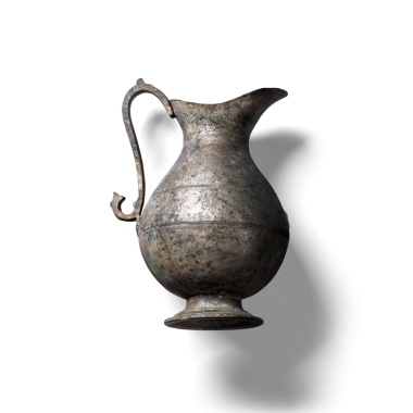 Kıvrımlı saplı eski bir metal sürahi. Sıvıları dökmek için tasarlanmış..