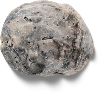 Yuvarlak, desenli bir nesne bir taşı andırıyor, pürüzsüz bir yüzeye sahip açık ve koyu renkli bir karışım sunuyor..