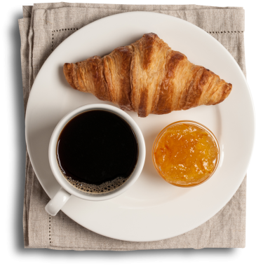 İçinde kruvasan, bir fincan kahve ve bir kavanoz portakal reçeli olan bir tabak. Kahvaltı için ideal..