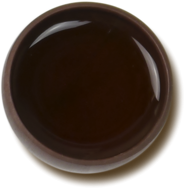 Parlak bir sıvıyla doldurulmuş küçük, koyu bir seramik kap, muhtemelen servis yapmak ya da batırmak için kullanılır..