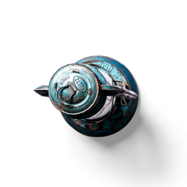 Eski, yıpranmış bir yangın musluğu yukarıdan görünüyor, benzersiz tasarımı ve patinasıyla sergileniyor..