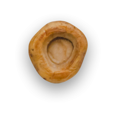 Yuvarlak, içi boş ve desenli bir gıda maddesinin, bir fındık veya tohumu andıran yakın plan görüntüsü..